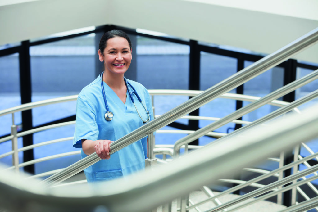Une femme souriante dans un escalier en métal appartenant au personnel médical de l'Hôpital de Lyon.